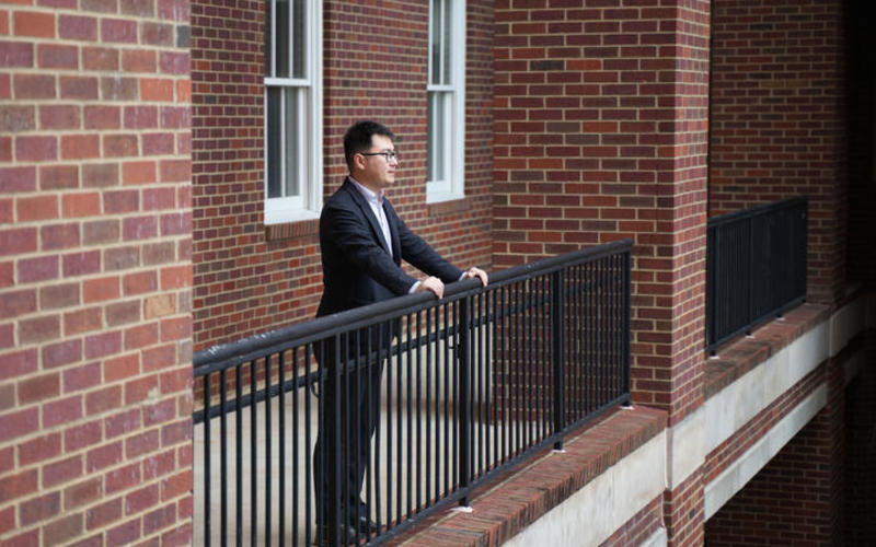 Edward Wang looking over railing into courtyard. 